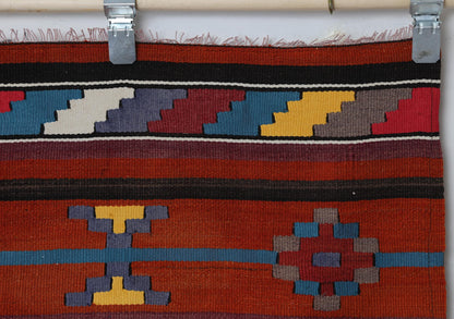 Close-up of handmade wool runner rug showing zigzag pattern in gold, teal and red