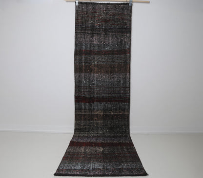 2x9 vintage Turkish flatweave runner rug hanging showing long black and red striped pattern