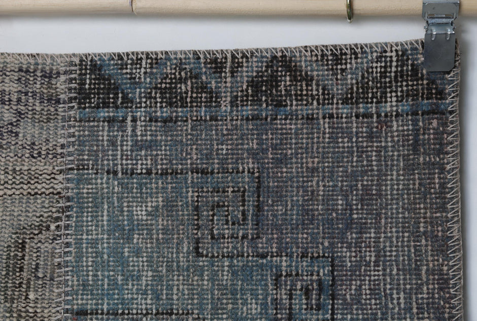 Close-up of handmade wool cotton runner rug showing faded blue vintage weave with tan patch