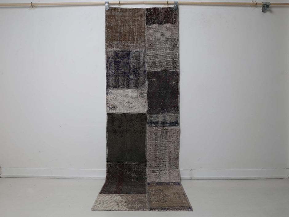 2x8 vintage patchwork runner rug hanging showing multicolor blocks in brown, tan and dark navy