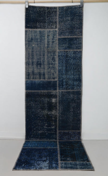 Close-up of vintage Turkish runner rug texture showing deep blue distressed woven panels