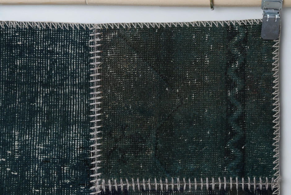 Close-up of handmade wool cotton runner rug showing deep teal green distressed weave with zigzag seam