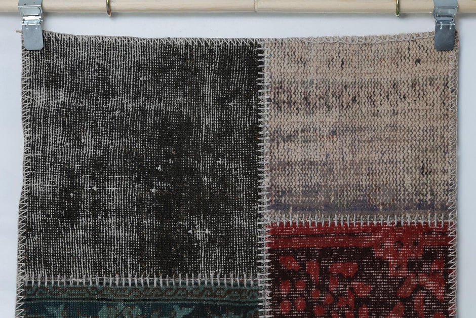 Detail shot of vintage Turkish patchwork rug panel showing black and red distressed weave block