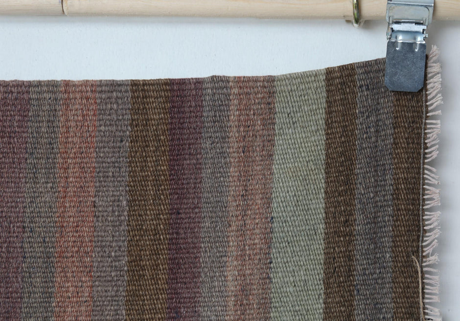 Close-up of handmade wool runner rug showing striped weave with fringe edge