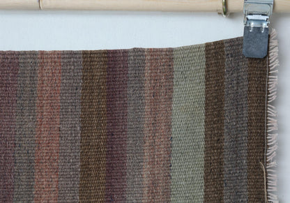 Close-up of handmade wool runner rug showing striped weave with fringe edge