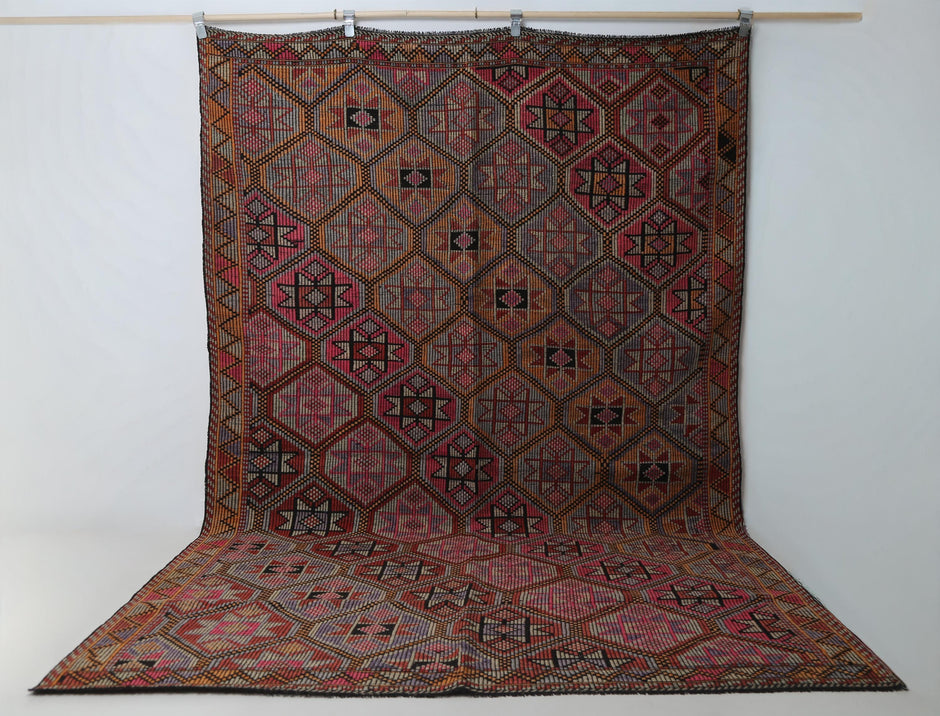 6x10 vintage Turkish flatweave rug hanging showing full red oriental octagon medallion pattern
