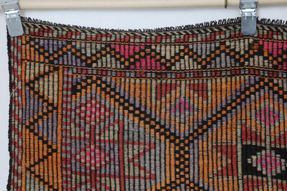Detail shot of vintage Turkish rug weave showing red and orange geometric lattice with black accents