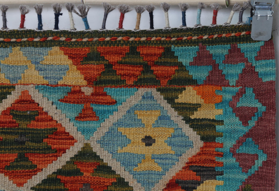 Close-up of handmade wool kilim rug showing bold turquoise and red geometric weave