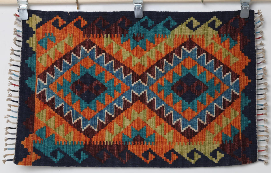 2x3 vintage Turkish kilim rug hanging showing blue diamond medallion on orange tribal background