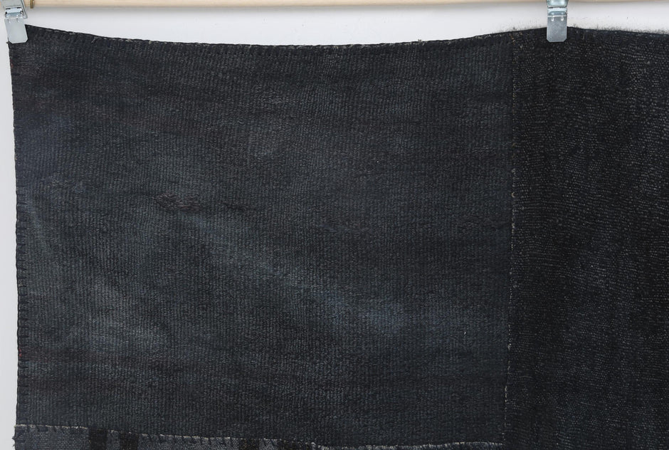 Close-up of stitched geometric patchwork panel on dark blue hemp rug