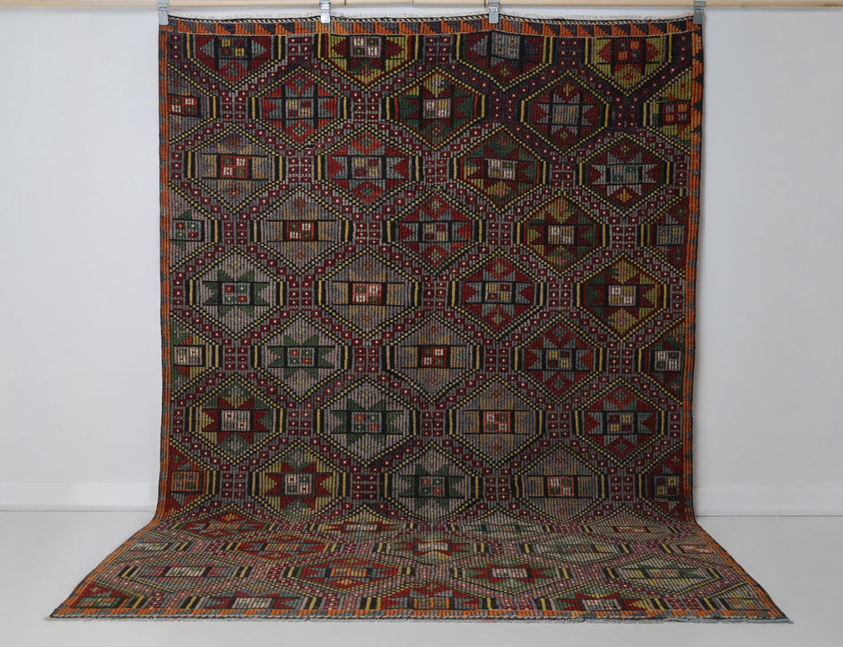 6x9 vintage Turkish kilim rug hanging showing full multicolor tribal geometric pattern