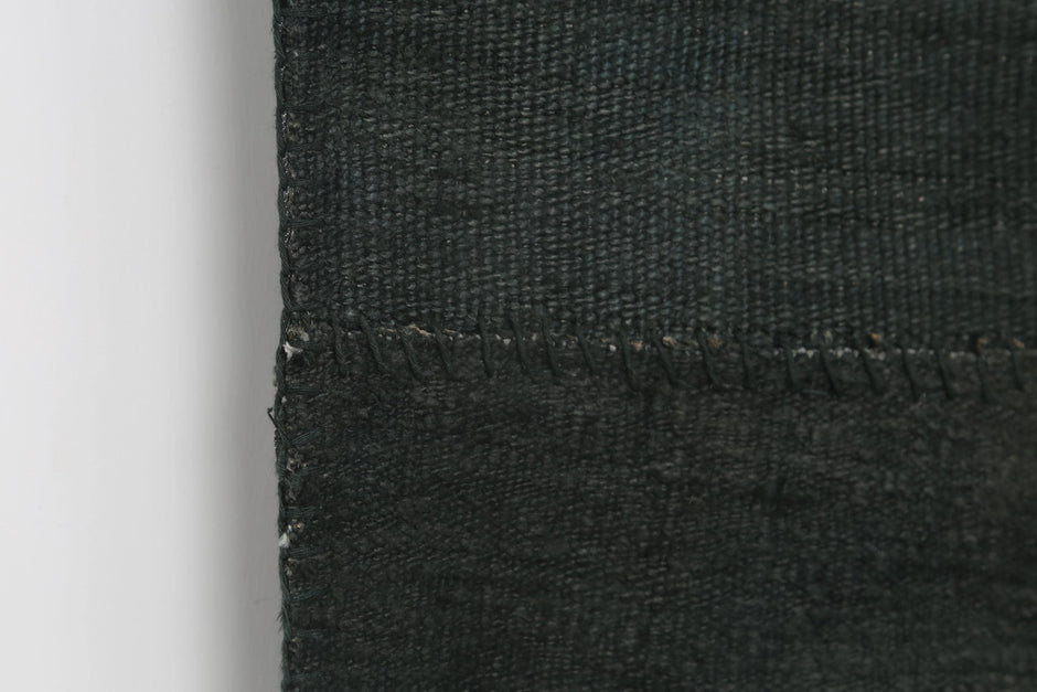 Back side of handmade deep green hemp patchwork rug showing weave texture
