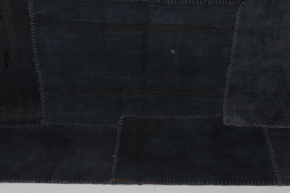 Close-up of handmade Turkish rug edge showing dark indigo hemp patchwork texture