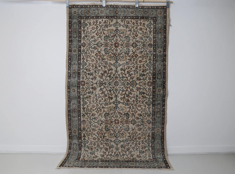 Beige green floral rug close-up, distressed weave texture