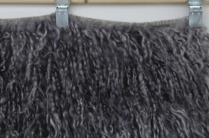 Back side of handwoven charcoal gray and smoky purple tulu rug showing weave base