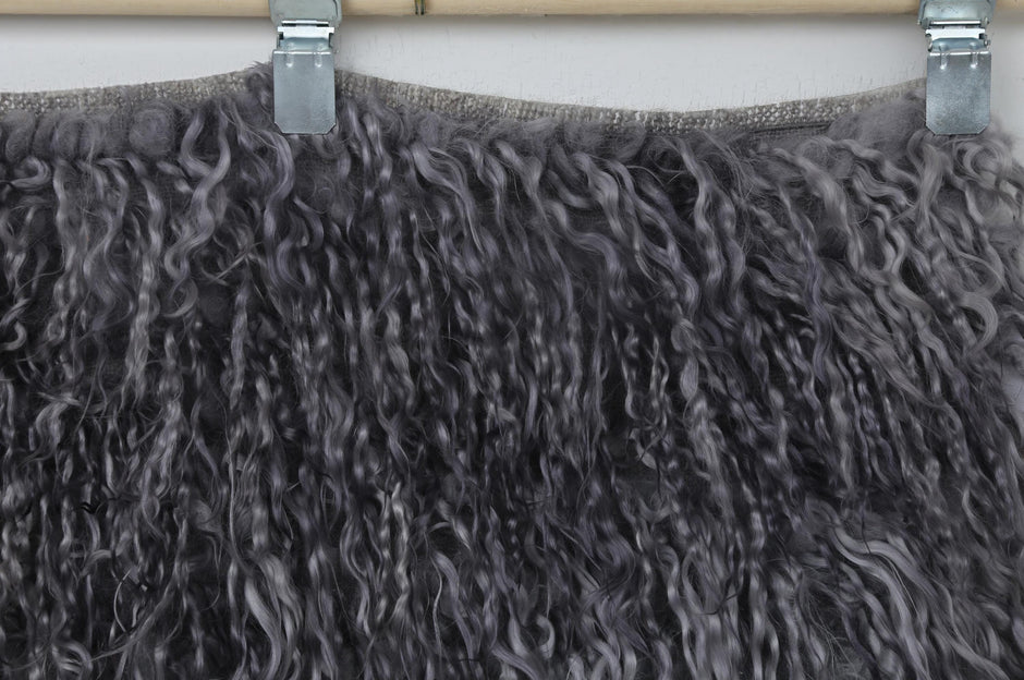 Back side of handwoven charcoal gray and smoky purple tulu rug showing weave base