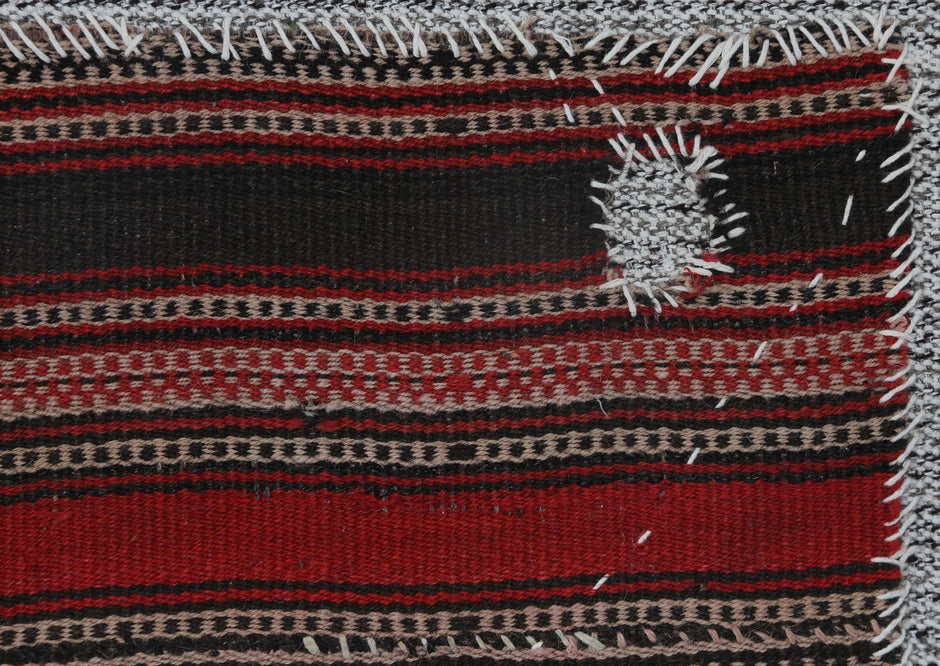 Back side of handmade red and black wool tapestry rug showing weave texture