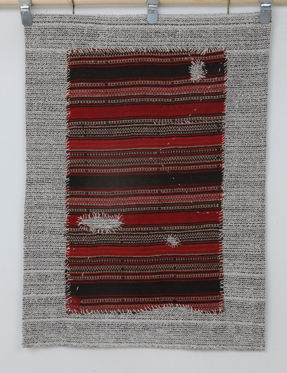  Close-up of hand-stitched detail on red and black striped tapestry