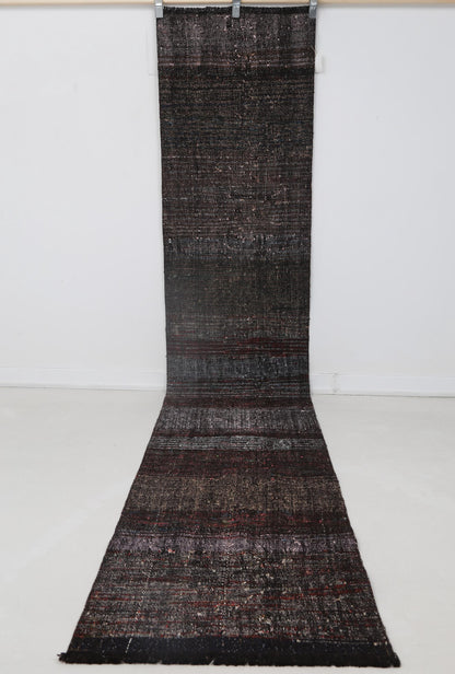 Close-up of faded red tonal detail on black striped runner rug