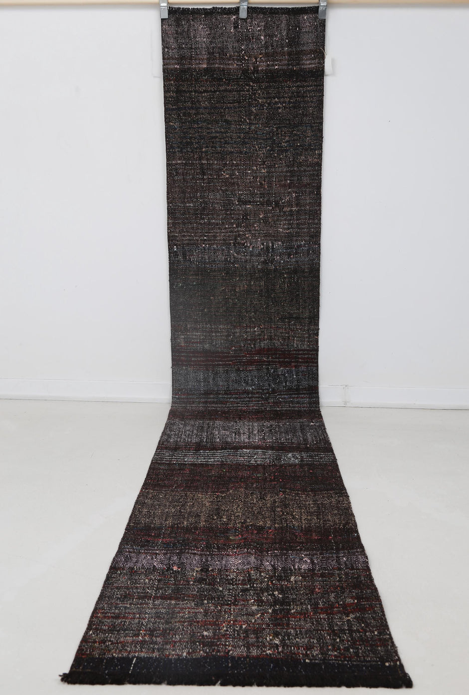 Close-up of faded red tonal detail on black striped runner rug