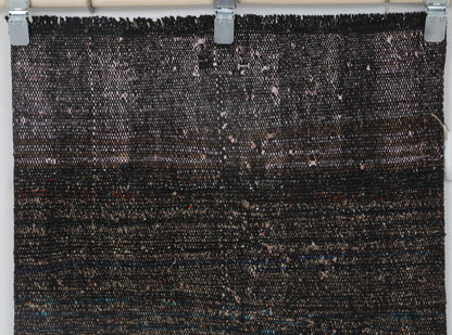 Back side of handmade black and red flatweave runner showing weave texture
