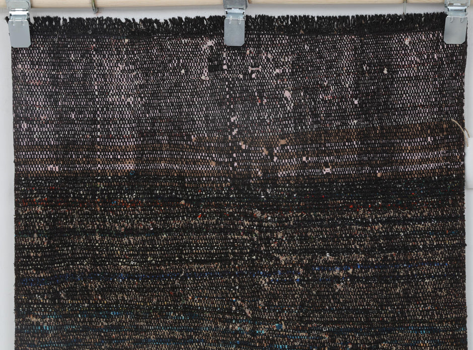 Back side of handmade black and red flatweave runner showing weave texture