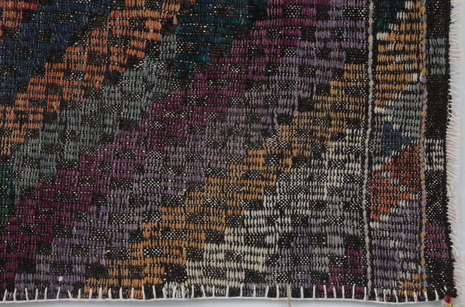 Back side of handmade multicolor wool geometric tapestry showing weave texture