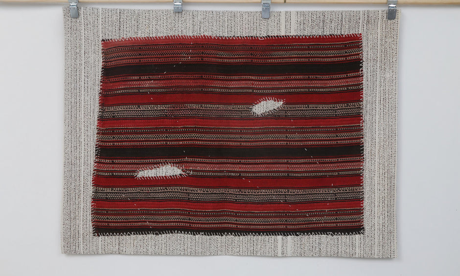  Close-up of hand-stitched detail on red and black striped tapestry
